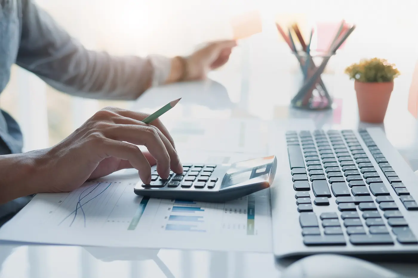 Analista calculando custos com calculadora e notebook