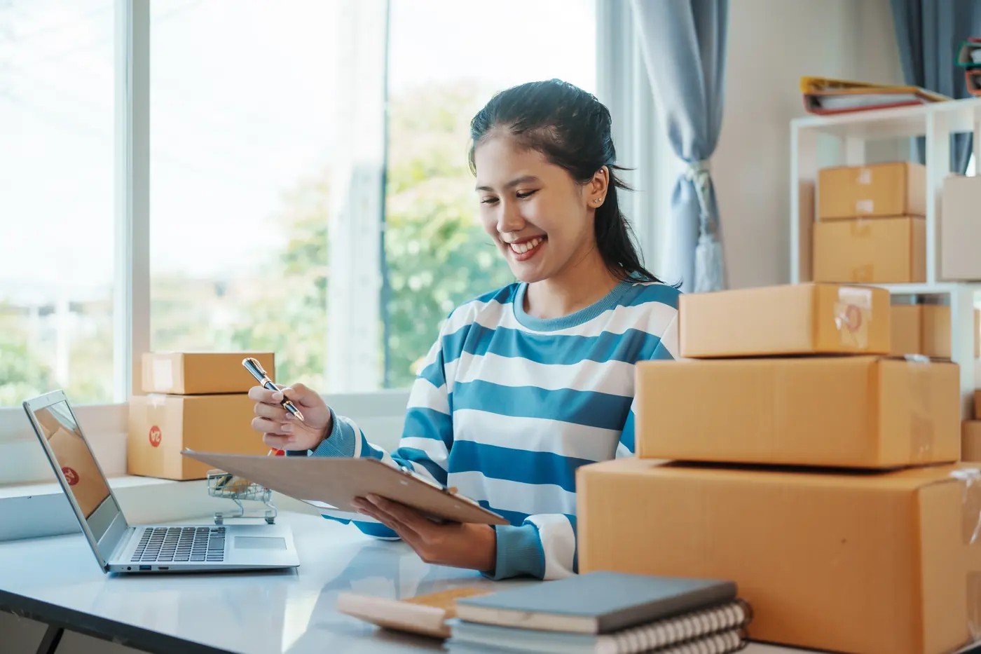 Vendedora de e-commerce conferindo pedidos no notebook